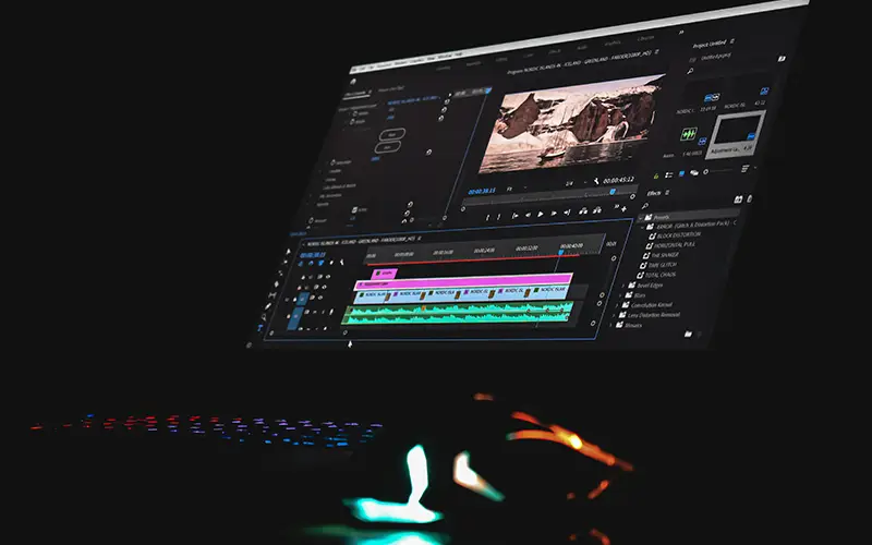 Computer screen displaying video editing software with a timeline and preview in a dark room.